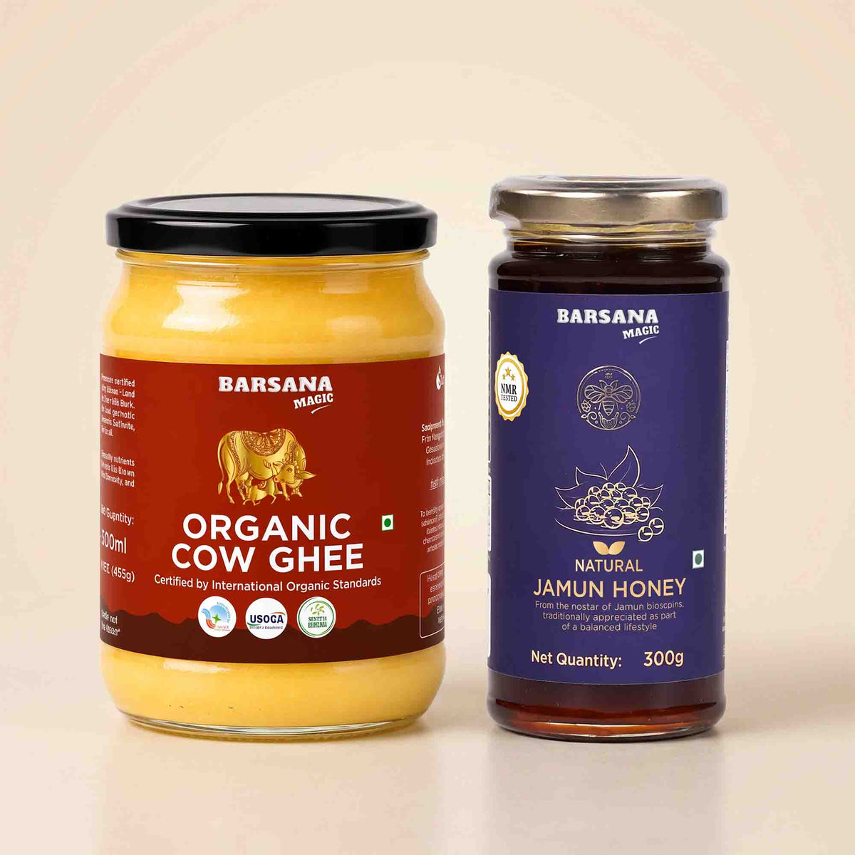 Barsana Magic and Two jars of organic ghee and natural jamun honey on a light beige background. The left jar contains yellow organic cow ghee with a red label and black lid, and the right jar contains dark brown natural jamun honey with a blue label and silver lid.