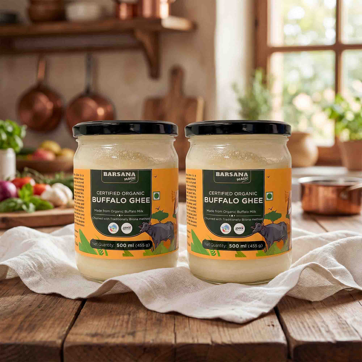 Barsana Magic and Two jars of Certified Organic Buffalo Ghee on a wooden table with a kitchen background.