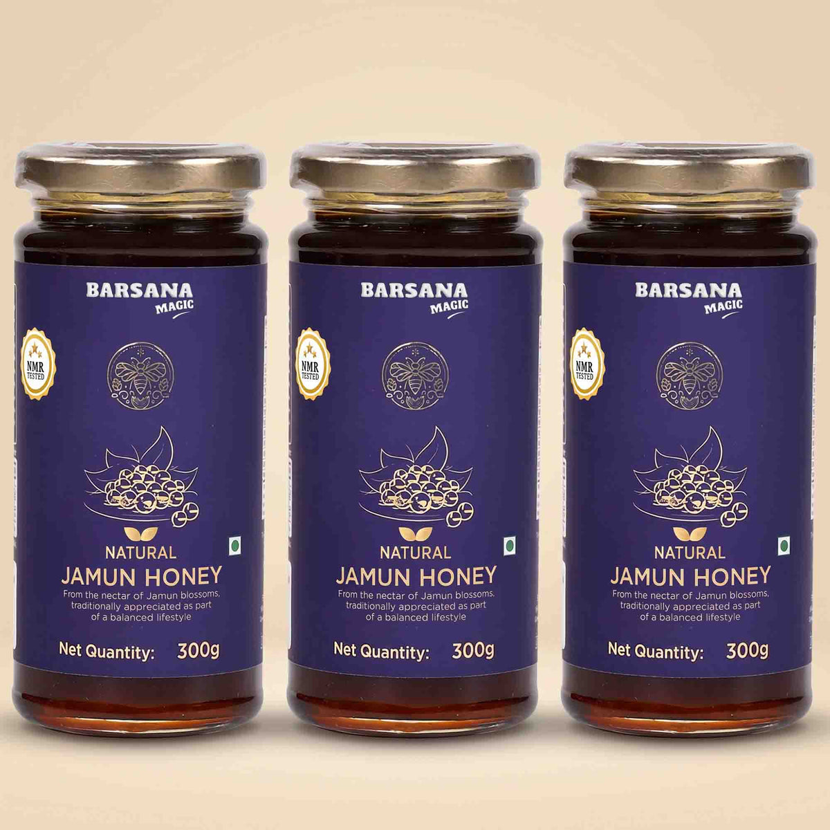 Barsana Magic and Three glass jars of Barsana Magic Natural Jamun Honey arranged side by side on a light beige background. Each jar has a dark blue label with gold and white text and graphics, topped with a silver metal lid.