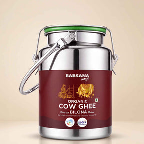 Barsana Magic and A stainless steel milk canister of Barsana Magic Organic Cow Ghee with a dark red label and a green lid seal, set against a solid beige background.