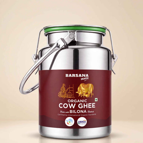Barsana Magic and A stainless steel milk canister of Barsana Magic Organic Cow Ghee with a dark red label and a green lid seal, set against a solid beige background.