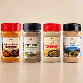 Barsana Magic and Four spice powder bottles from Himalaya Sansad Kosh displayed side-by-side on a light beige background. The bottles contain different spices (Masala Chogong, Shatavari Masala, Chana Masala, and Panchamrit Masala) and are equipped with red, black, red, and black caps respectively.