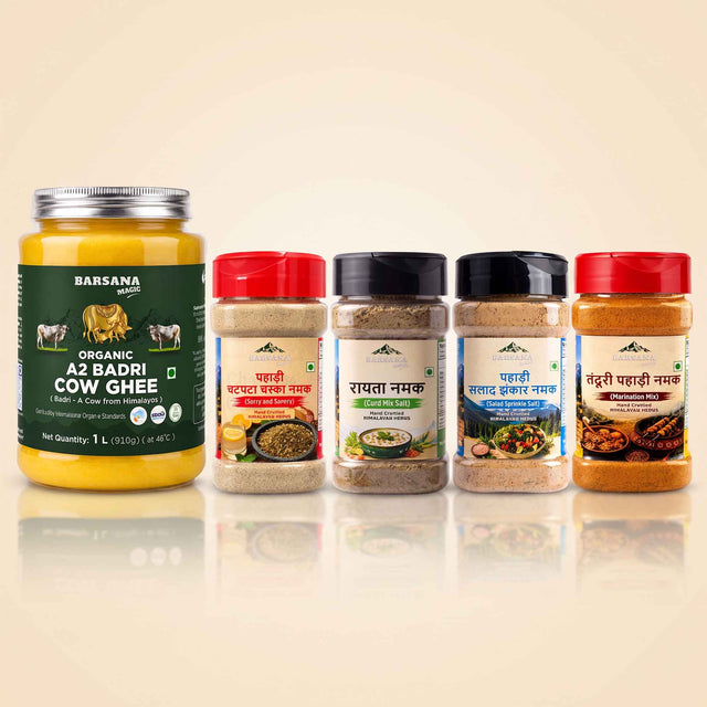Barsana Magic and A set of BarSana brand Indian spices and ghee products displayed on a reflective beige surface against a light beige background. The set includes a large jar of BarSana Organic A2 Badri Cow Ghee on the left, and four spice jars with red, black, and white lids on the right.