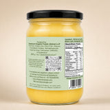 Barsana Magic and A glass jar of yellow butter with a black lid, showing the back label with text, a QR code, and nutrition facts against a plain beige background.