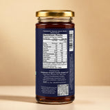 Barsana Magic and A rear view of a jar of honey with a gold lid and a dark blue label showing the nutrition facts, set against a solid beige background.