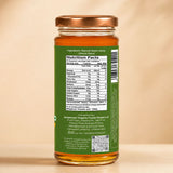 Barsana Magic and A glass jar of natural neem honey with a copper-colored metal lid and a green label showing the nutrition facts panel, set against a warm beige background.