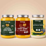 Barsana Magic and Three jars of Barsana Magic brand ghee arranged side by side on a warm beige background. The left jar is Organic A2 Badri Cow Ghee with a dark green label; the middle jar is Organic Cow Ghee made with Bilona butter, with a dark red label; the right jar is Certified Organic Buffalo Ghee with a yellow and green label.