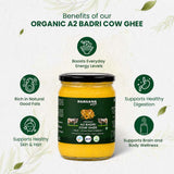 Barsana Magic and A jar of Barsana Organic A2 Badri Cow Ghee centered on a light textured background with green benefit callouts around it. The jar has a black lid and a dark green label showing a cow illustration and product text.