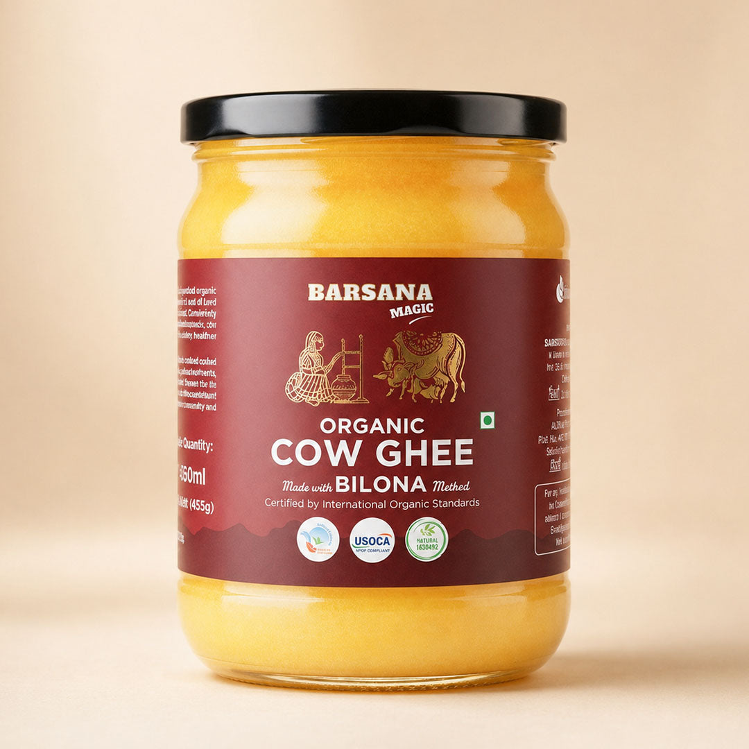 Barsana Magic and A glass jar of Barsana Magic Organic Cow Ghee, filled with golden yellow ghee and featuring a dark maroon label with a black lid, set against a solid beige background.