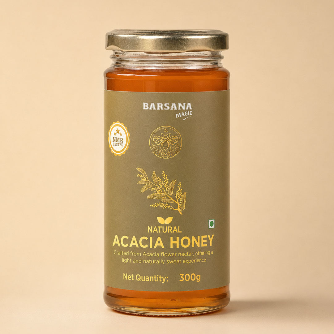 Barsana Magic and A 300g glass jar of Barsana Magic Natural Acacia Honey, featuring a metallic olive green label with gold lettering and a silver metal lid, set against a solid beige background.