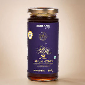 Barsana Magic and A 300g glass jar of Barsana Magic Natural Jamun Honey, featuring a deep purple label with gold and white text and graphics, topped with a metallic gold lid, set against a warm beige background.