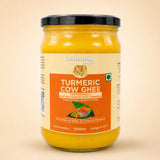 Barsana Magic and A 500ml glass jar of Barsana Turmeric Cow Ghee, showing the bright yellow ghee through the clear glass, with a cream and orange label and a black lid, set against a solid beige background.