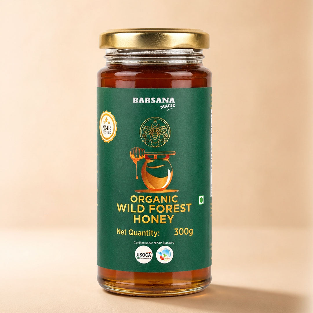 Barsana Magic and A 300g glass jar of Barsana Magic Organic Wild Forest Honey with a gold lid and a dark green label, set against a solid beige background.