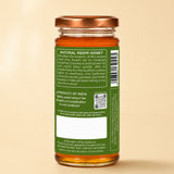 Barsana Magic and A glass jar of Natural Neem Honey shown from the back, featuring a green label with product details, a barcode, and a blank white space, topped with a copper-colored lid on a warm beige background.