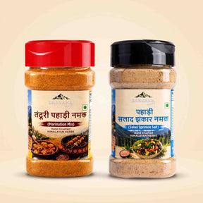 Barsana Magic and Two jars of Darshana brand Himalayan spices on a light beige background. The left jar has a red lid and contains Marination Mix, while the right jar has a black lid and contains Salad Sprinkle Salt.