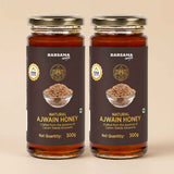Barsana Magic and Two jars of Barsana Magic Natural Ajwain Honey, 300g each, arranged side-by-side on a light beige background. The jars are made of amber glass, showing the golden-brown honey inside, and are sealed with gold-colored metal lids.