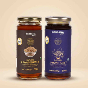 Barsana Magic and Two glass jars of Barsana Spices honey on a beige background. The left jar is labeled 'Natural Ajwain Honey' with a dark brown label, and the right jar is labeled 'Natural Jamun Honey' with a deep purple label.