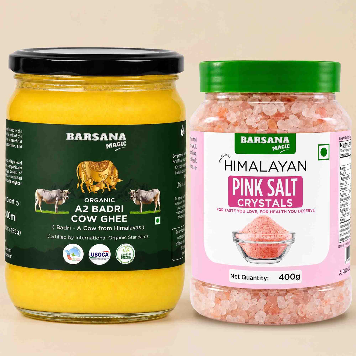Barsana Magic and Two jars of Barsana Magic products on a light beige background: a large jar of Organic A2 Badri Cow Ghee with a black lid and dark green label, and a smaller jar of Himalayan Pink Salt Crystals with a green lid and pink label.
