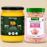 Barsana Magic and Two jars of Barsana Magic products on a light beige background: a large jar of Organic A2 Badri Cow Ghee with a black lid and dark green label, and a smaller jar of Himalayan Pink Salt Crystals with a green lid and pink label.