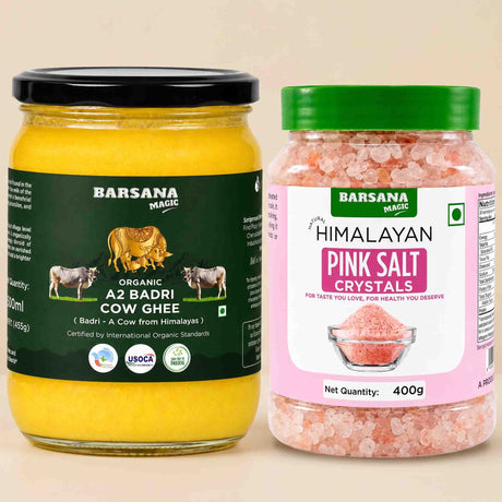 Barsana Magic and Two jars of Barsana Magic products on a light beige background: a large jar of Organic A2 Badri Cow Ghee with a black lid and dark green label, and a smaller jar of Himalayan Pink Salt Crystals with a green lid and pink label.