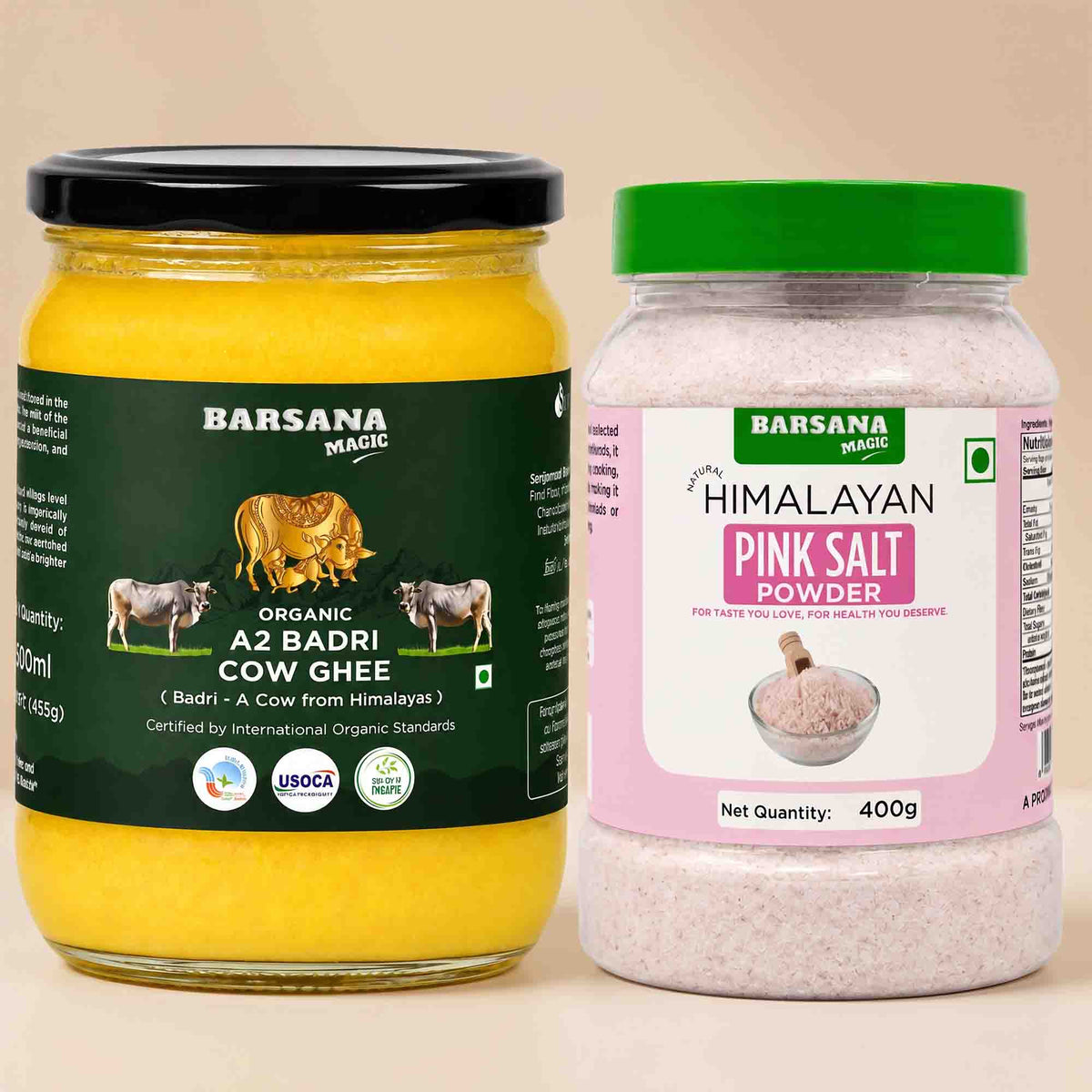 Barsana Magic and Two Barsana Magic products on a beige background: a large glass jar of Organic A2 Badri Cow Ghee with a black lid and dark green label, and a plastic jar of Himalayan Pink Salt Powder with a green lid and pink label.