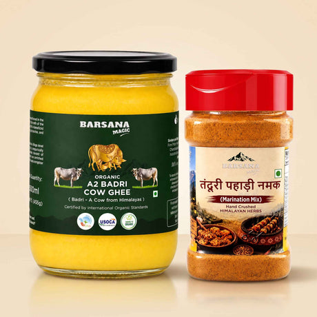 Barsana Magic and A glass jar of Barsana Organic Az Badri Cow Ghee with a black lid and dark green label, next to a plastic jar of Barsana Taddri Pahaadi Namak (Himalayan Marination Mix) with a red lid and cream label, set against a warm beige background.