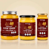 Barsana Magic and Three glass jars of Barsana Organic Cow Ghee arranged side by side on a light beige background. The left jar has a silver lid, the middle has a black lid, and the right has a gold lid.