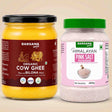 Barsana Magic and Two Barsana Magic products on a beige background: a large jar of Organic Cow Ghee with a black lid and dark red label, and a plastic jar of Himalayan Pink Salt powder with a green lid and pink label.