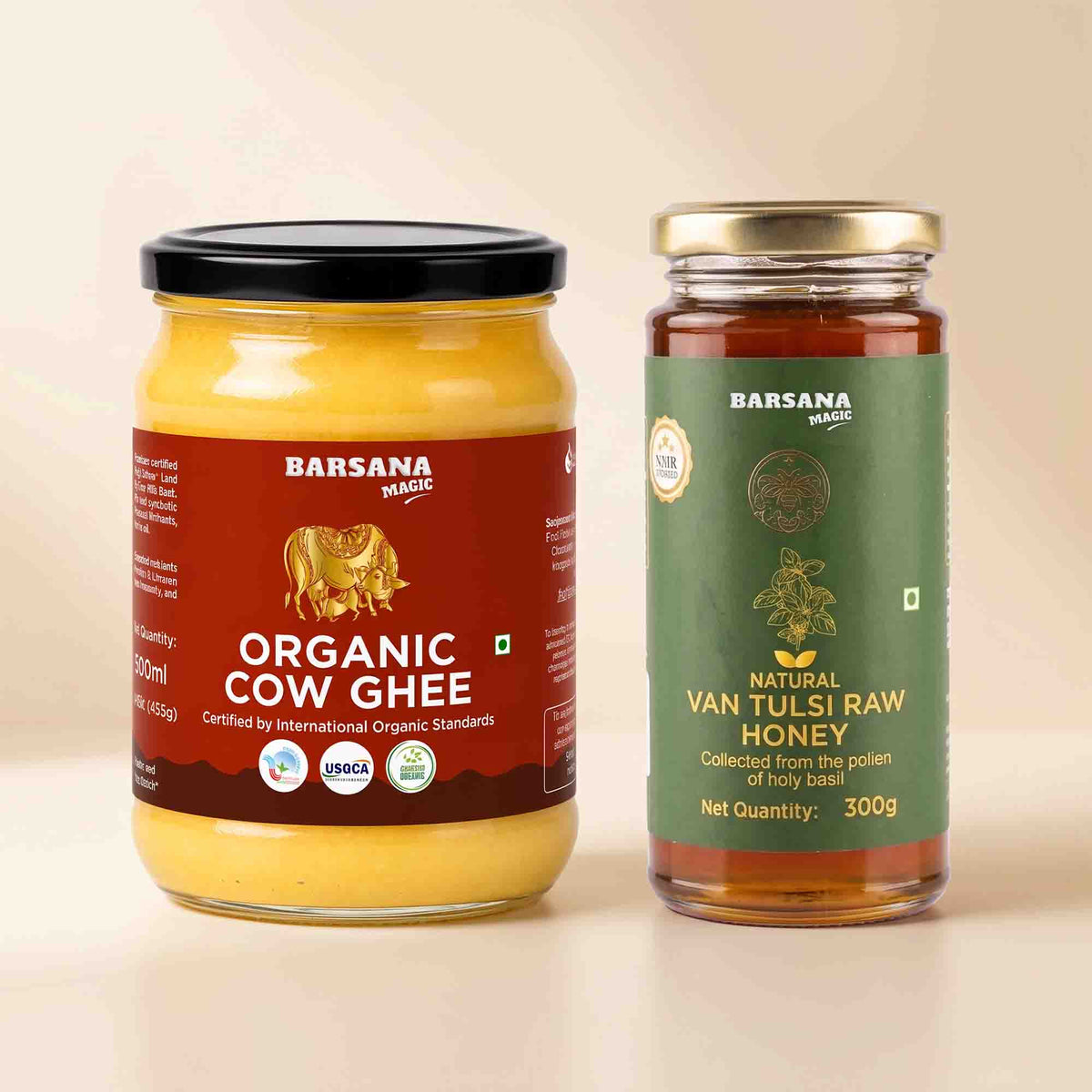 Barsana Magic and Two glass jars of products on a light beige background: a large jar of Organic Cow Ghee with a black lid and brown label, and a smaller jar of Natural Van Tulsi Raw Honey with a gold lid and green label.