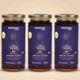 Barsana Magic and Three glass jars of Barsana Magic Natural Jamun Honey arranged side by side on a light beige background. Each jar has a dark blue label with gold and white text and graphics, topped with a silver metal lid.