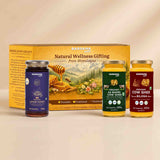 Barsana Magic and Legacy gift set containing three jars of organic and traditional honey/ghee alongside its yellow cardboard packaging box, displayed on a light beige surface against a matching beige background.