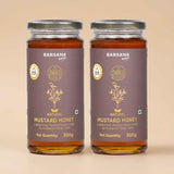 Barsana Magic and Two glass jars of Barsana Brand Natural Mustard Honey with dark brown labels and silver lids, set against a solid beige background.