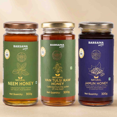 Barsana Magic and Three glass jars of Barsana Magic honey arranged side by side on a beige background. The jars are labeled Natural Neem Honey, Natural Van Tulsi Raw Honey, and Natural Jamun Honey, with green, gold, and blue labels respectively.