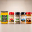 Barsana Magic and A set of five Indian spices and spreads from Barhana Brand arranged on a light beige background. The set includes a large jar of Yellow Nutle Dairy Spread on the left, followed by four clear plastic spice jars with red and black lids: Papai Chutney, Ramta Namak, Papai Samad Bhasha Namak, and Hantui Papai Namak.