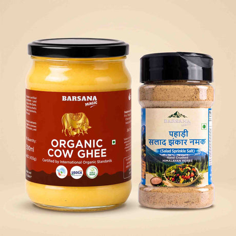 Barsana Magic and A glass jar of Barsana Magic Organic Cow Ghee with a black lid and a brown label, next to a clear plastic shaker bottle of Barsana Magic Salad Spinkle Salt with a black lid and a white/blue label, set against a solid beige background.