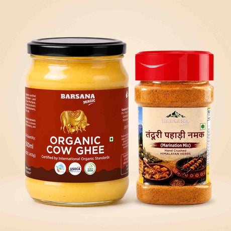 Barsana Magic and A glass jar of Barsana Magic Organic Cow Ghee with a black lid and a brown label, next to a plastic bottle of Barsana Magic Tendu Pahaade Namak (Himalayan Marination Mix) with a red lid, set against a solid beige background.