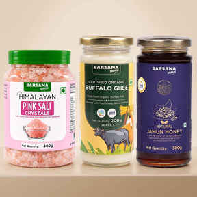 Barsana Magic and Three Barsana Magic products displayed side-by-side on a light beige shelf: a jar of Himalayan Pink Salt Crystals with a green lid, a glass jar of Certified Organic Buffalo Ghee with a gold lid, and a dark glass jar of Natural Jamun Honey with a purple lid.