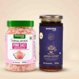 Barsana Magic and A 400g jar of Barsana Magic Himalayan Pink Salt Crystals with a green lid and pink label, standing next to a 300g jar of Barsana Magic Natural Jamun Honey with a dark purple label and silver lid, set against a solid beige background.