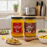 Barsana Magic and  Two jars of dairy spreads on a kitchen counter with food items around.